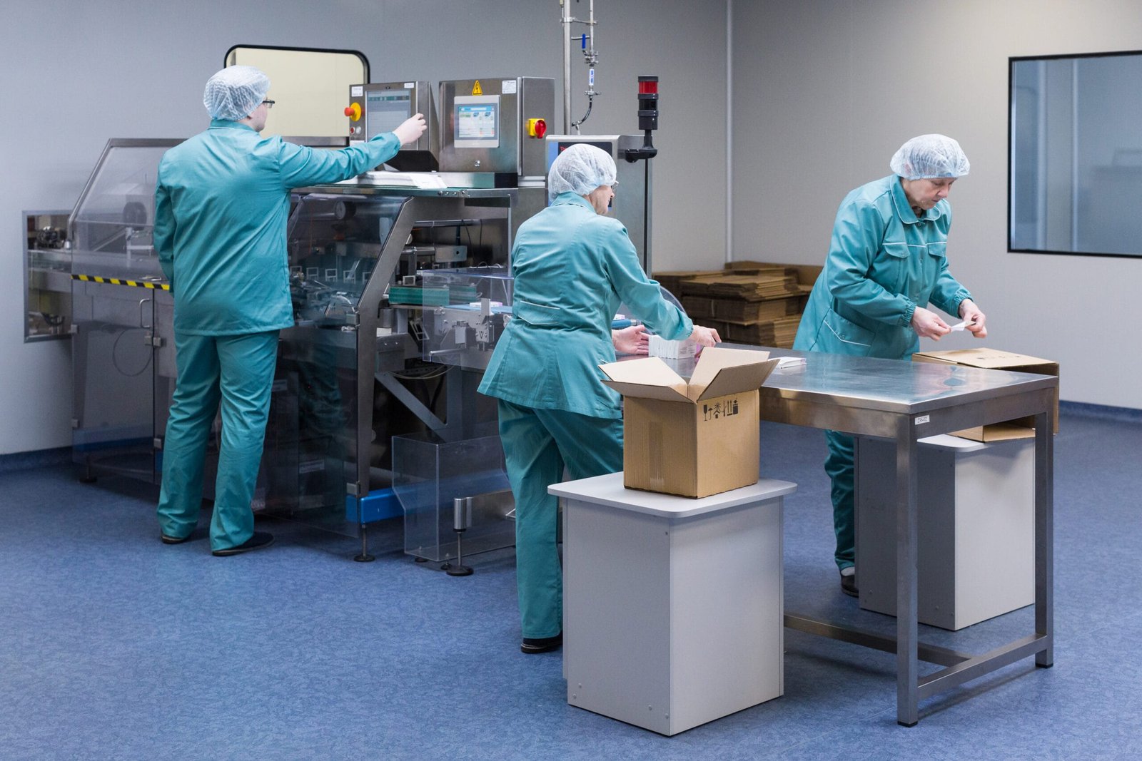 Pharmaceutical technicians work in sterile working conditions at pharmaceutical factory. Scientists wearing protective clothing