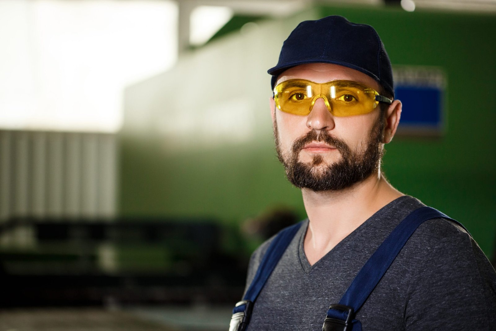 Portrait of worker in overalls, industrial steel factory background.