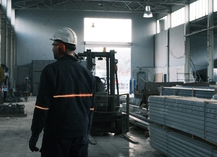 A worker in protective gear supervises operations in a modern factory.