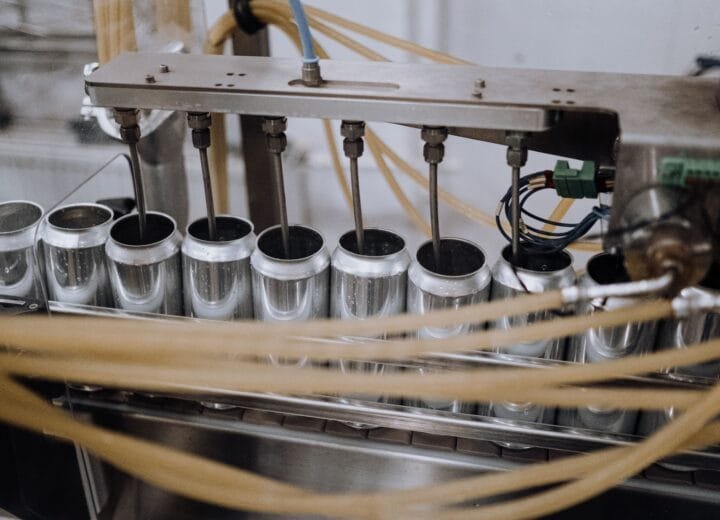 Close-up of automated machinery on a beverage can filling the production line inside a manufacturing plant