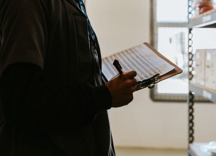 Industrial worker managing inventory in a warehouse with a clipboard and checklist.