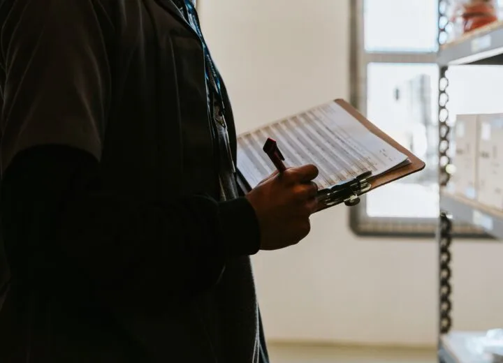 Industrial worker managing inventory in a warehouse with a clipboard and checklist.