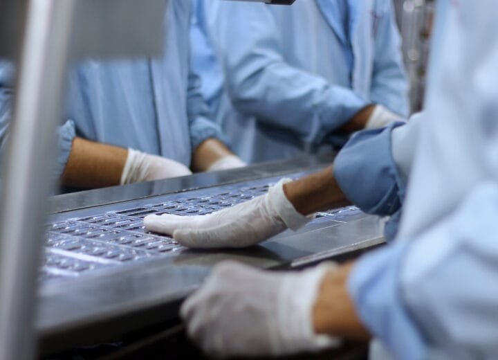 Workers in a pharmaceutical facility packaging tablets
