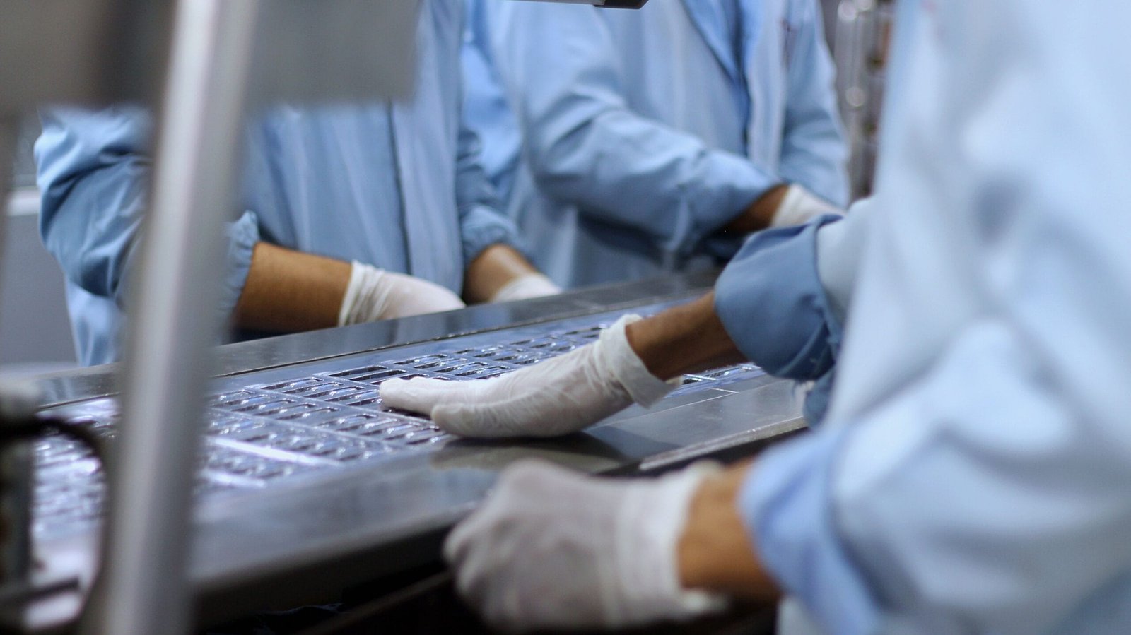 Workers in a pharmaceutical facility packaging tablets