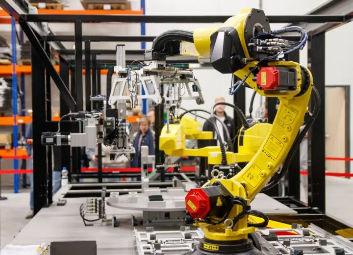 A yellow industrial robotic arm in action at a modern manufacturing facility