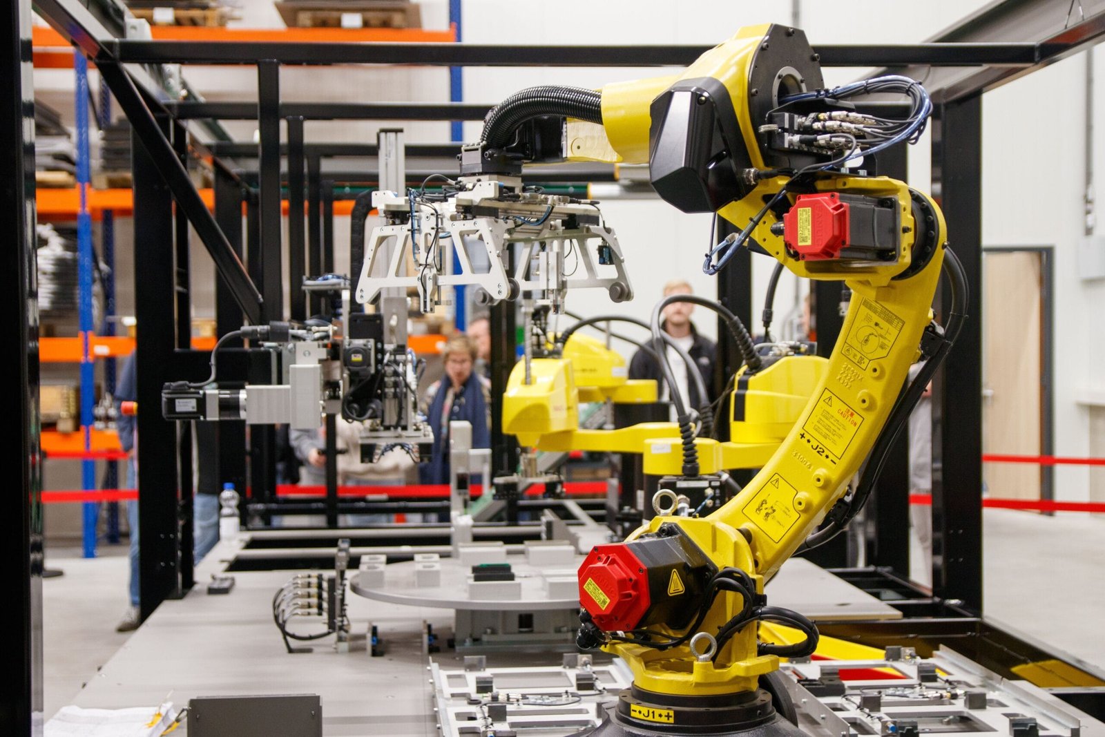A yellow industrial robotic arm in action at a modern manufacturing facility