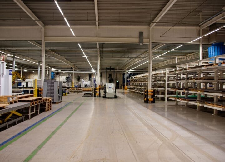 Spacious industrial warehouse interior featuring machinery and storage shelves