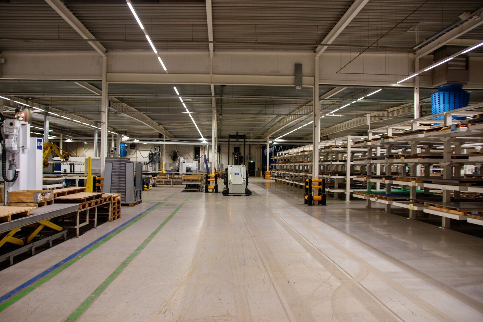 Spacious industrial warehouse interior featuring machinery and storage shelves