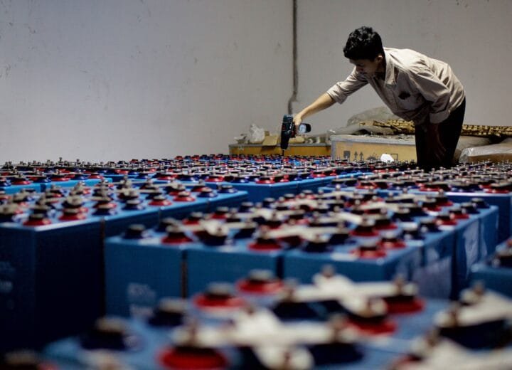 A worker checking industrial battery equipment inside a facility.