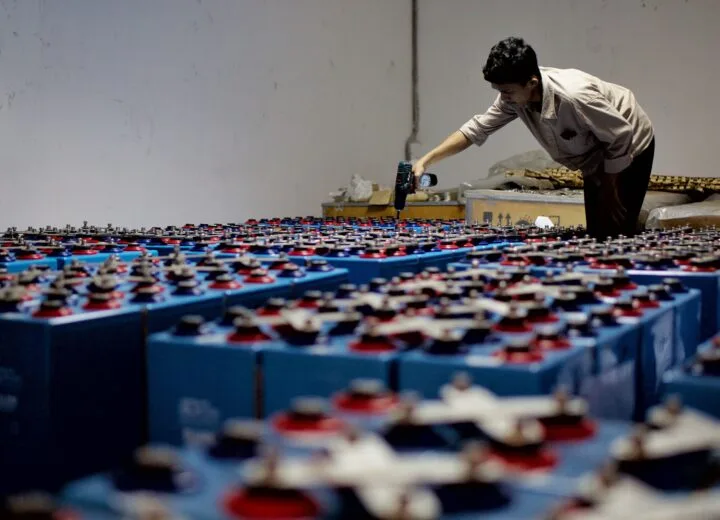 A worker checking industrial battery equipment inside a facility.