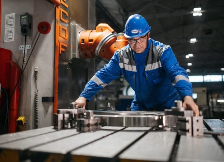 A worker in blue uniform operates machinery in an industrial factory setting