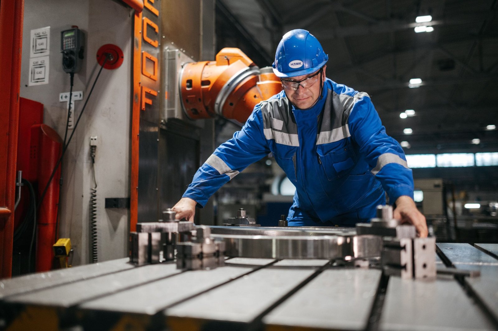A worker in blue uniform operates machinery in an industrial factory setting