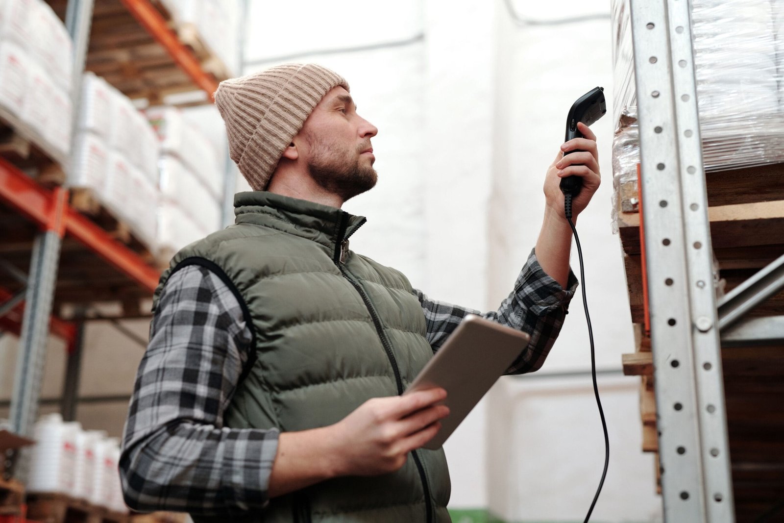 Male warehouse staff scanning inventory with handheld scanner and tablet indoors