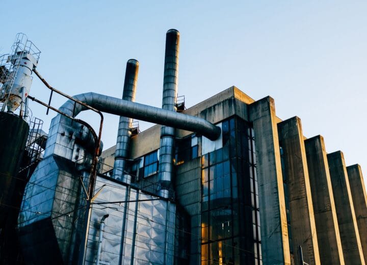 A contemporary industrial factory structure with smokestacks at sunset, showcasing modern architecture.