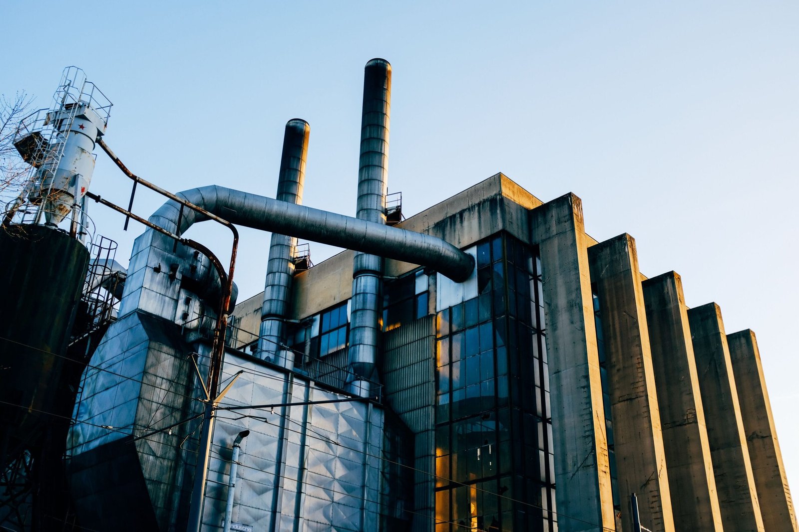 A contemporary industrial factory structure with smokestacks at sunset, showcasing modern architecture.