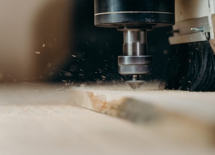 CNC machine in action, precisely cutting a wooden panel with sawdust flying.