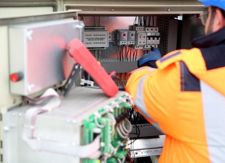 Professional engineer inspecting industrial electrical circuit board, ensuring safety standards.