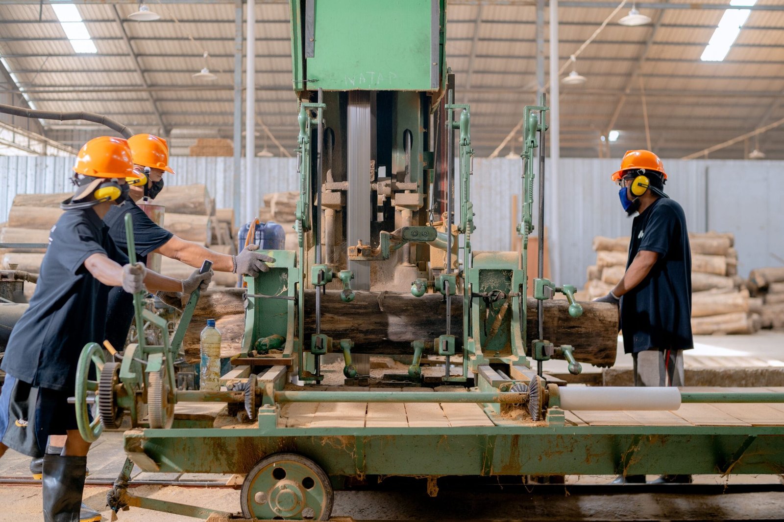 Industrial lumber processing with workers operating machinery in a factory setting