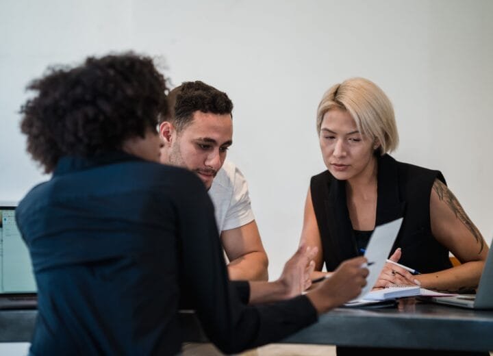 Diverse team engaged in a focused meeting at a contemporary workplace, discussing project details