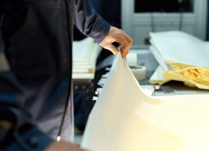 An industrial worker manages large sheets in a manufacturing setting, focusing on precision and quality
