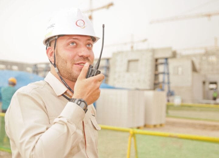 Male construction worker using radio on a building site, wearing a safety helmet, communicating effectively