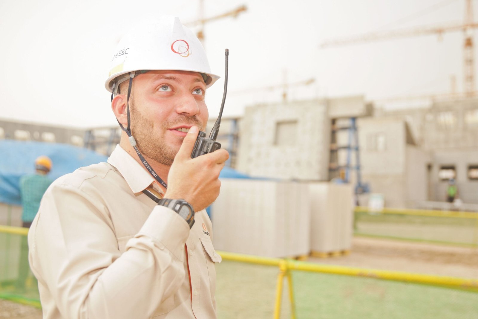 Male construction worker using radio on a building site, wearing a safety helmet, communicating effectively