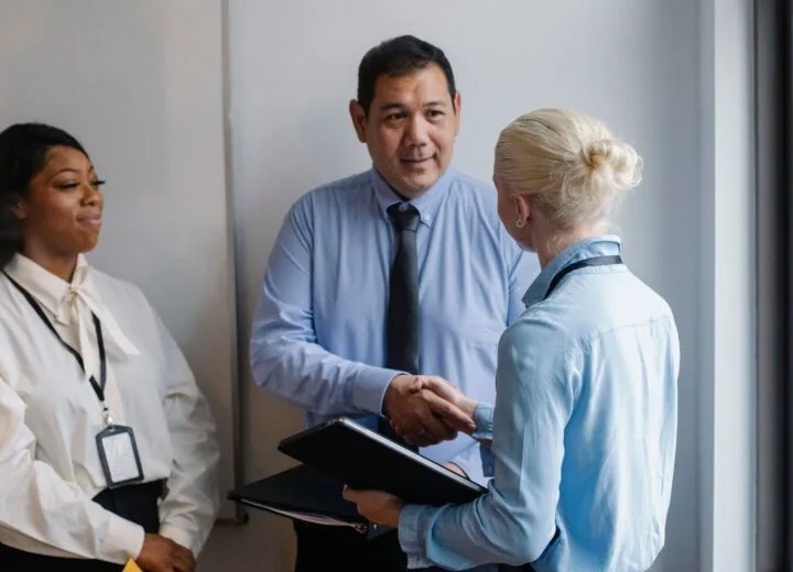 Diverse professionals in an office engaged in a positive business handshake, fostering teamwork and collaboration