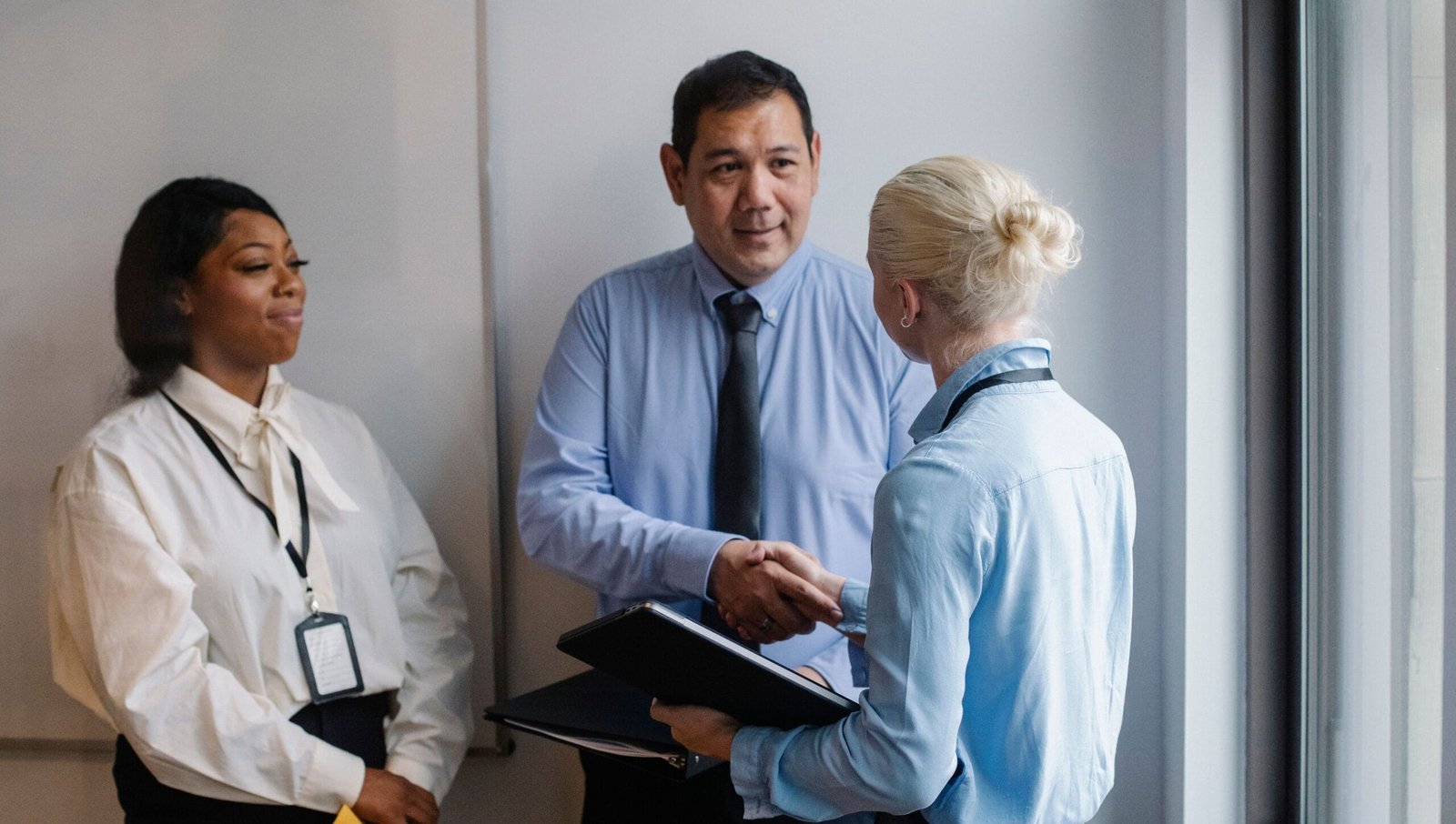 Diverse professionals in an office engaged in a positive business handshake, fostering teamwork and collaboration