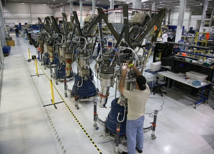 A technician inspects rocket engine machinery inside a modern industrial factory