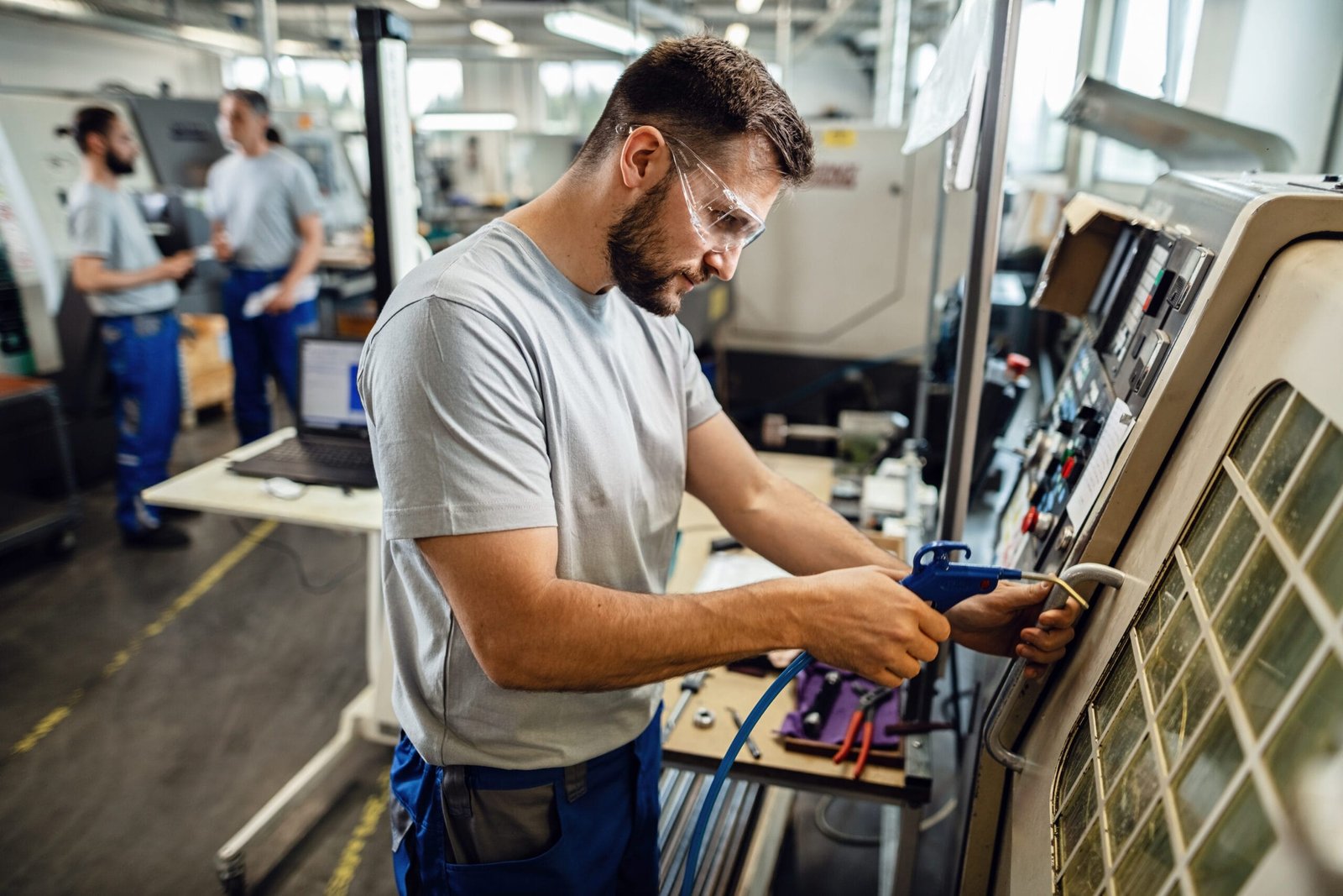 Young engineer operating a CNC machine in production line in a factory.