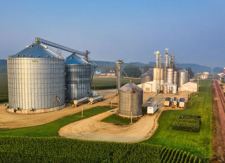 Aerial view of grain bins, conveyors and tanker trucks at an industrial site relevant to manufacturing consulting firms